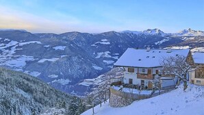 Un paysage montagneux enneigé avec un bâtiment de style chalet doté d’un balcon et d’un mur en pierre.