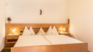 Un lit double avec une tête de lit en bois, deux tables de chevet avec des lampes et un petit objet décoratif accroché au mur.