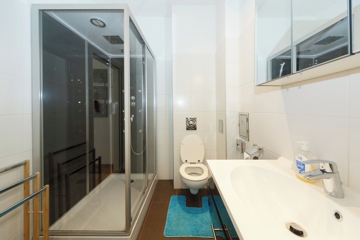 A modern bathroom with a glass-enclosed shower, a toilet, and a sink with a mirror above.