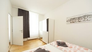 A bedroom with two beds, a large window with curtains, a door, and a zebra artwork on the wall. - Apartment No. 13 in Vienna near Schönbrunn/Westbahnhof | Keyless Check-In (Wien)
