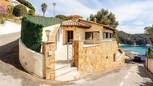 Ein Gebäude im mediterranen Stil mit einer steinernen Fassade, einem kleinen Balkon und einer Treppe zum Eingang.