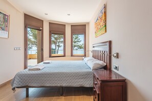 A bedroom with a bed, wooden nightstands, a painting, and a window with a view. - Villa 'Villa Con Infinity Pool' with Sea View, Wi-Fi and Air Conditioning (Lloret de mar)