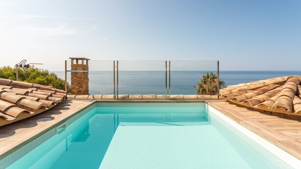 Ein Pool mit Meerblick, ein Rettungsturm und Liegestühle.