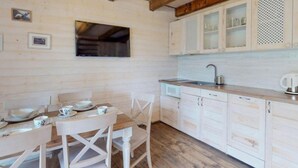 Eine rustikale Küche mit Holzschränken, einem Esstisch gedeckt mit Tellern und Tassen sowie einer Mikrowelle.