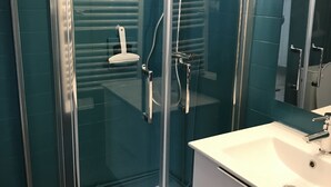 A modern bathroom with a glass shower enclosure, white sink, and teal tiled walls. - Studio 3B108 - Résidence le Grand Large - Le Barcares (Le Barcarès)