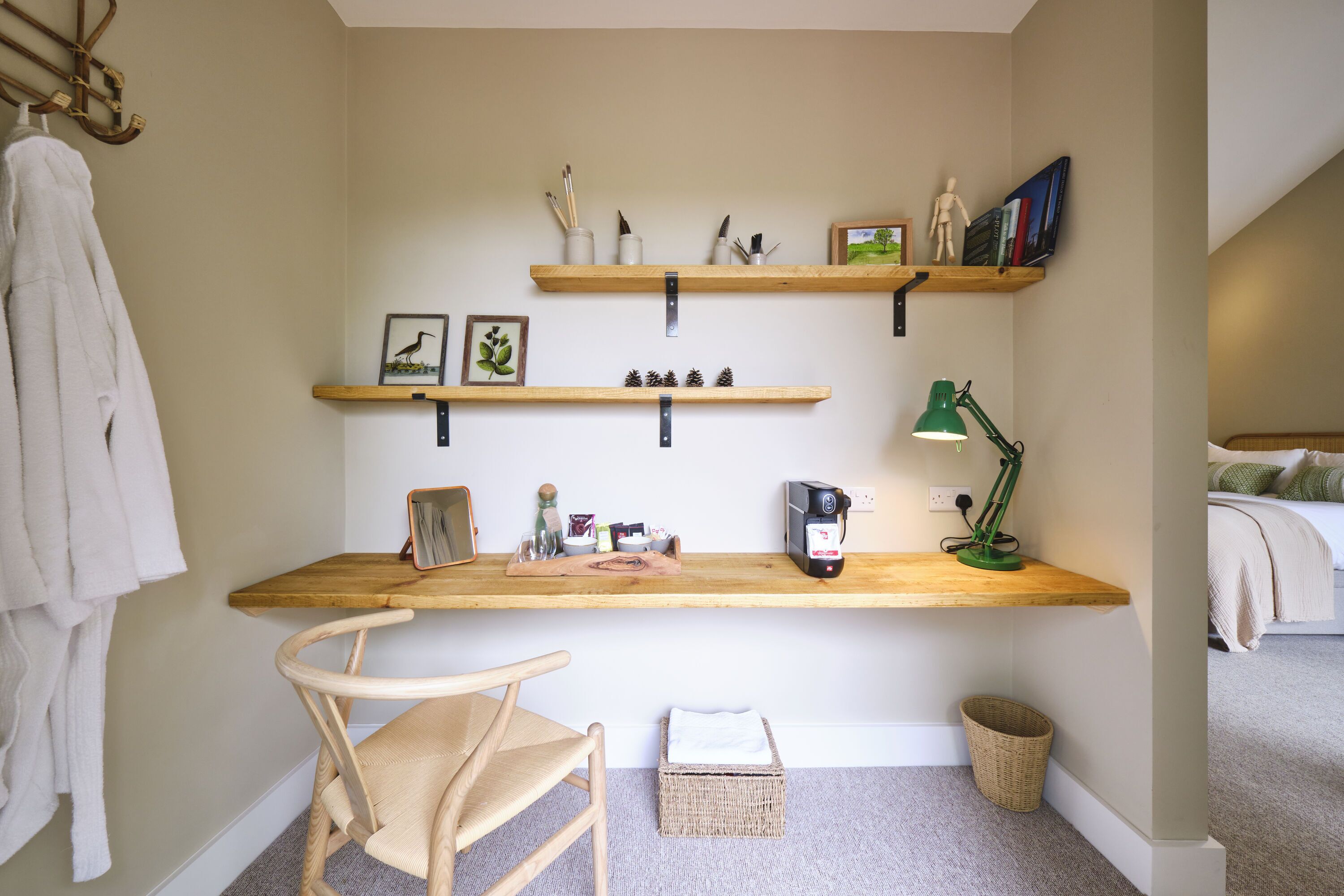 A bedroom with a bed, a bedside table, a chair, and a desk with shelves.