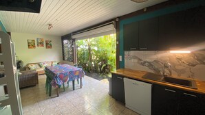 Cocina compacta con comedor, lavavajillas y ventana grande con vistas a un jardín.