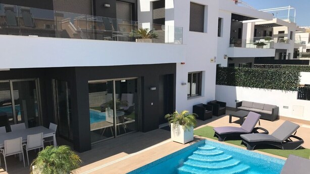 A modern building with a rooftop pool, outdoor seating, and a glass balustrade.