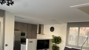 A modern living room with a dining area, a kitchen, and a staircase.