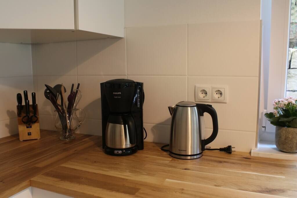 A kitchen with a coffee maker, a kettle, and a knife block on the counter.