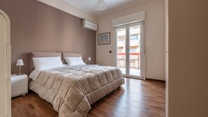 A bedroom with a bed, a nightstand, a lamp, an air conditioning unit, and a sliding glass door leading to an outdoor area. - Appartamento Libertà con terrazza by Wonderful Italy (Palermo)