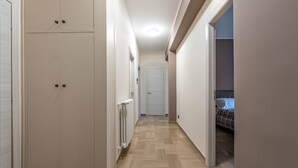 A narrow hallway with a wooden floor, a radiator, and a bed in the adjacent room. - Appartamento Libertà con terrazza by Wonderful Italy (Palermo)