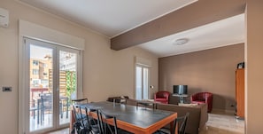 A modern living space with a dining area, a TV, and a red chair. - Appartamento Libertà con terrazza by Wonderful Italy (Palermo)
