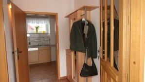 Ein Flur, der zu einer Küche mit Holzausstattung und einem Kleiderhaken führt.