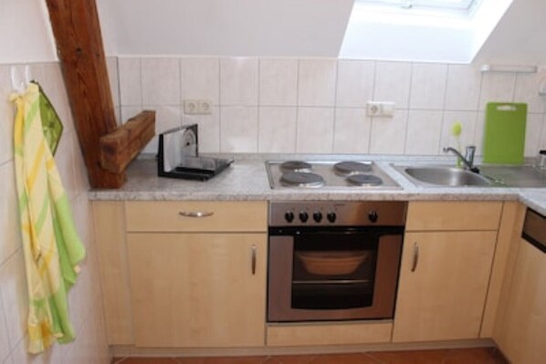 Een keuken met een inbouwoven, een kookplaat en een spoelbak.