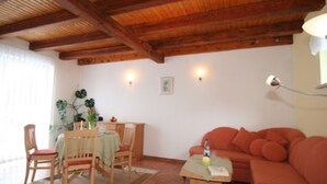 Ein Wohnzimmer mit Holzboden, einer Essecke mit Tisch und Stühlen sowie einem Sofa.