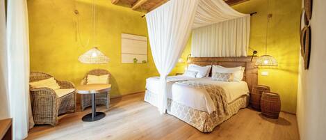 Une chambre à coucher avec un lit à baldaquin, des fauteuils en osier, une petite table et des tonneaux en bois.