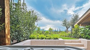 Un jacuzzi con vistas a un jardín ajardinado y un edificio al fondo.