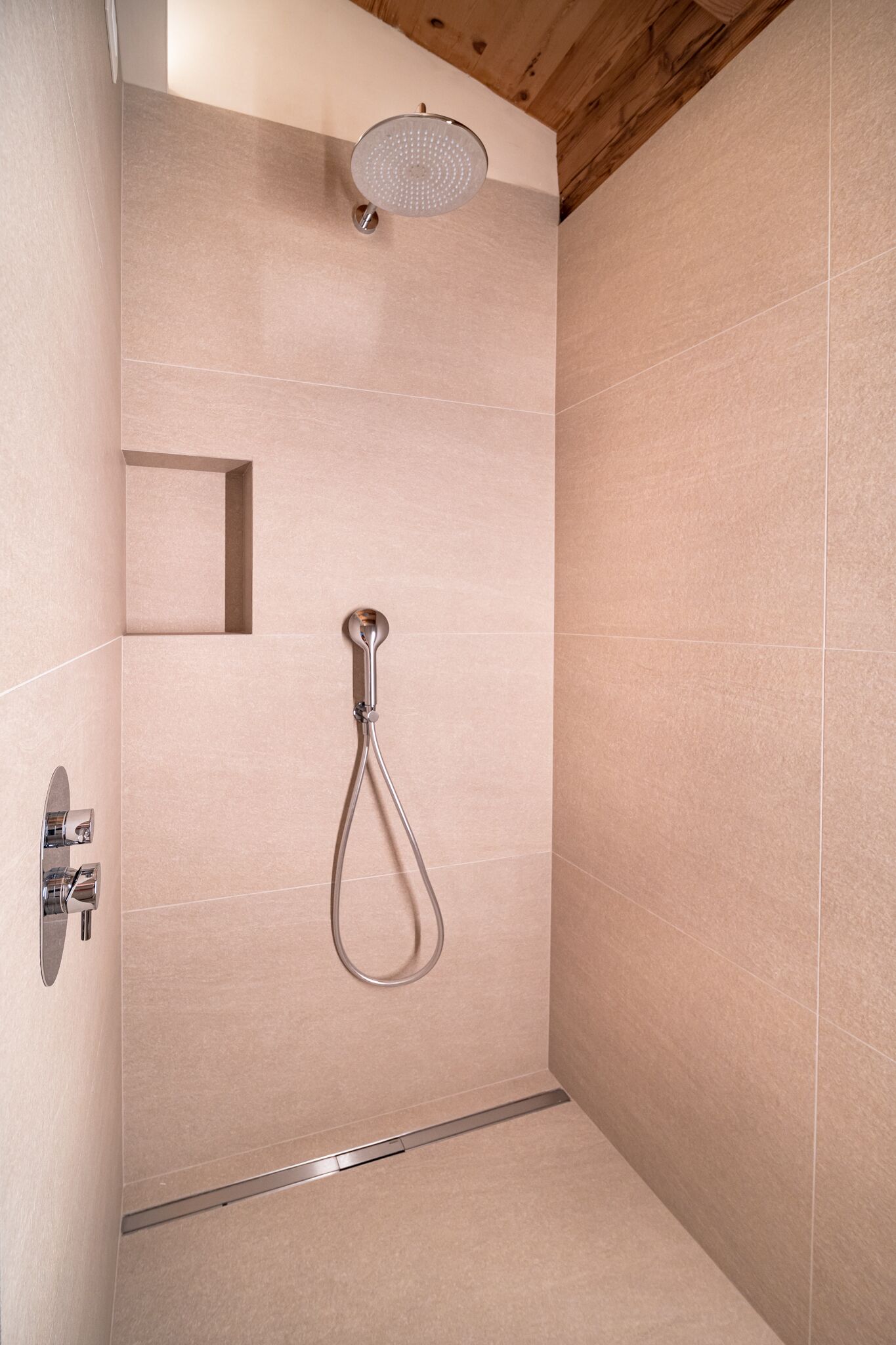 Una ducha moderna con cabezal de ducha manual y panel de control en la pared.