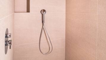 Una ducha moderna con cabezal de ducha manual y panel de control en la pared.