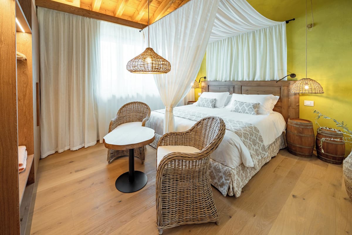 A bedroom with a bed, wicker chairs, a round table, and a canopy bed.