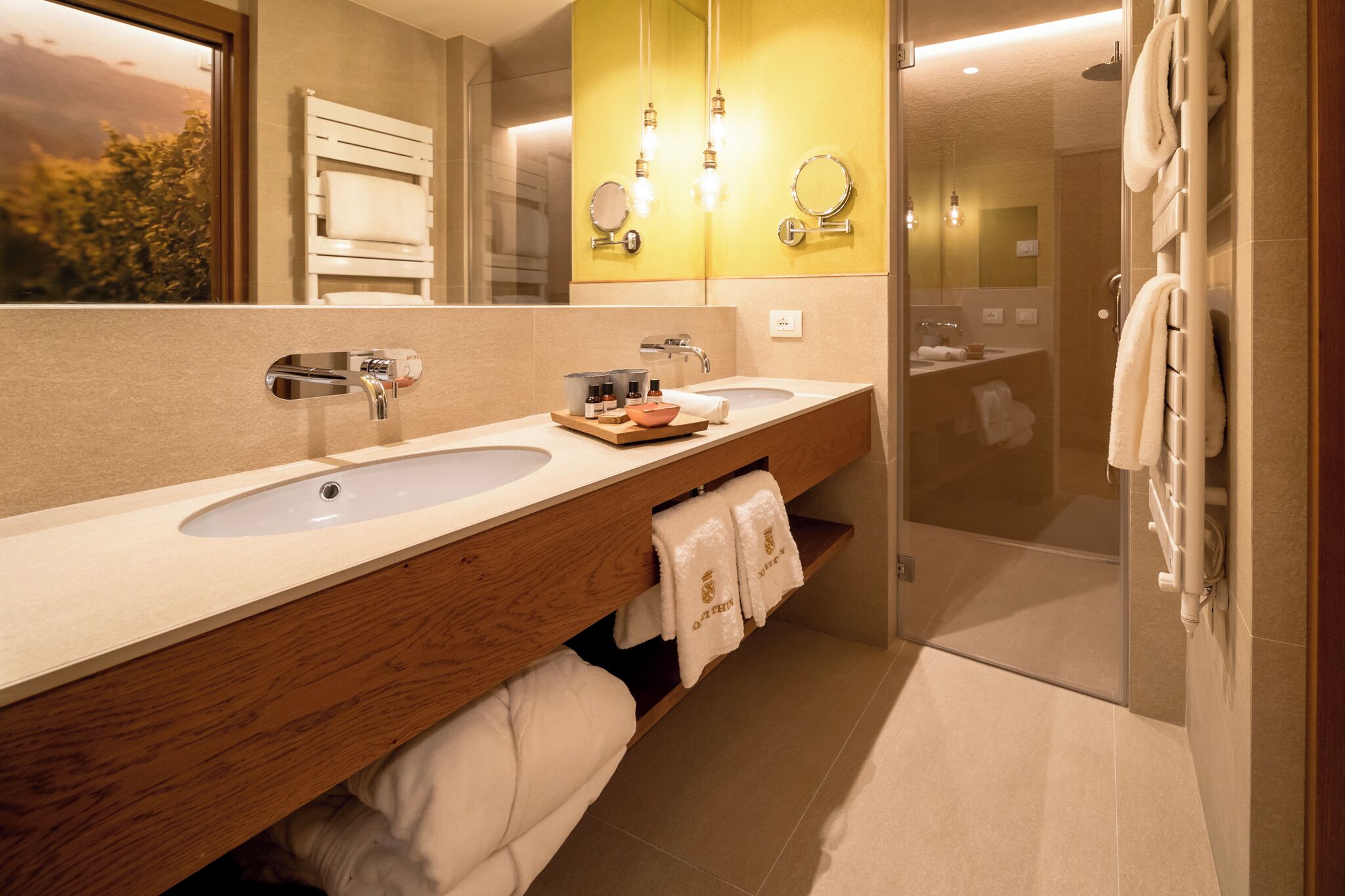 A modern bathroom with two sinks, a wooden vanity, and a glass shower enclosure.