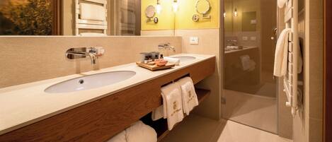 A modern bathroom with two sinks, a wooden vanity, and a glass shower enclosure.
