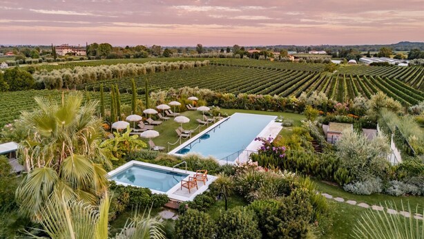 Un resort con dos piscinas rodeado de exuberantes jardines y palmeras.