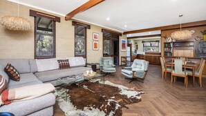 A spacious living room with a sofa, armchairs, a dining table, and a cowhide rug. - Ocean Close - Spacious  Beach House (Guilderton)