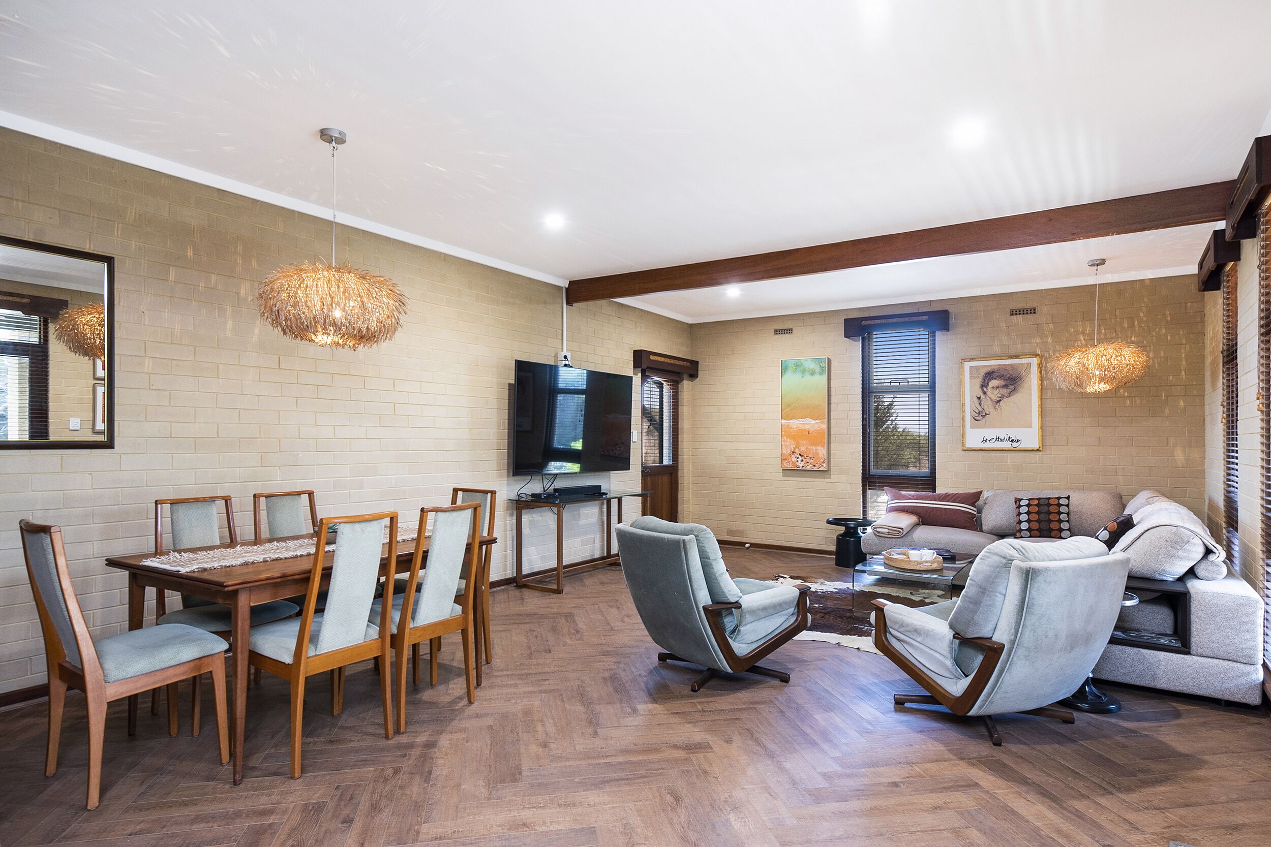 A spacious living area with a dining table, chairs, a sofa, and a television.