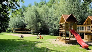 Une aire de jeux avec un toboggan, des balançoires et une structure d’escalade.