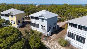 A coastal property with multiple buildings, including a two-story house with a large balcony and a smaller attached structure.