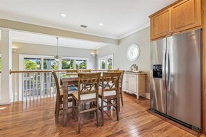 A spacious kitchen with a large stainless steel refrigerator, wooden cabinets, and a dining area with a table and chairs.