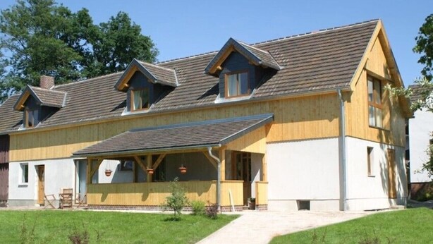 A two-story house with a sloped roof, a covered porch, and a front entrance. - Cozy apartment with a view of the beautiful Spreewald. (Burg)