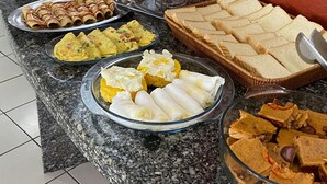 Een buffet met verschillende gerechten, zoals fruit, gebak en belegde broodjes.