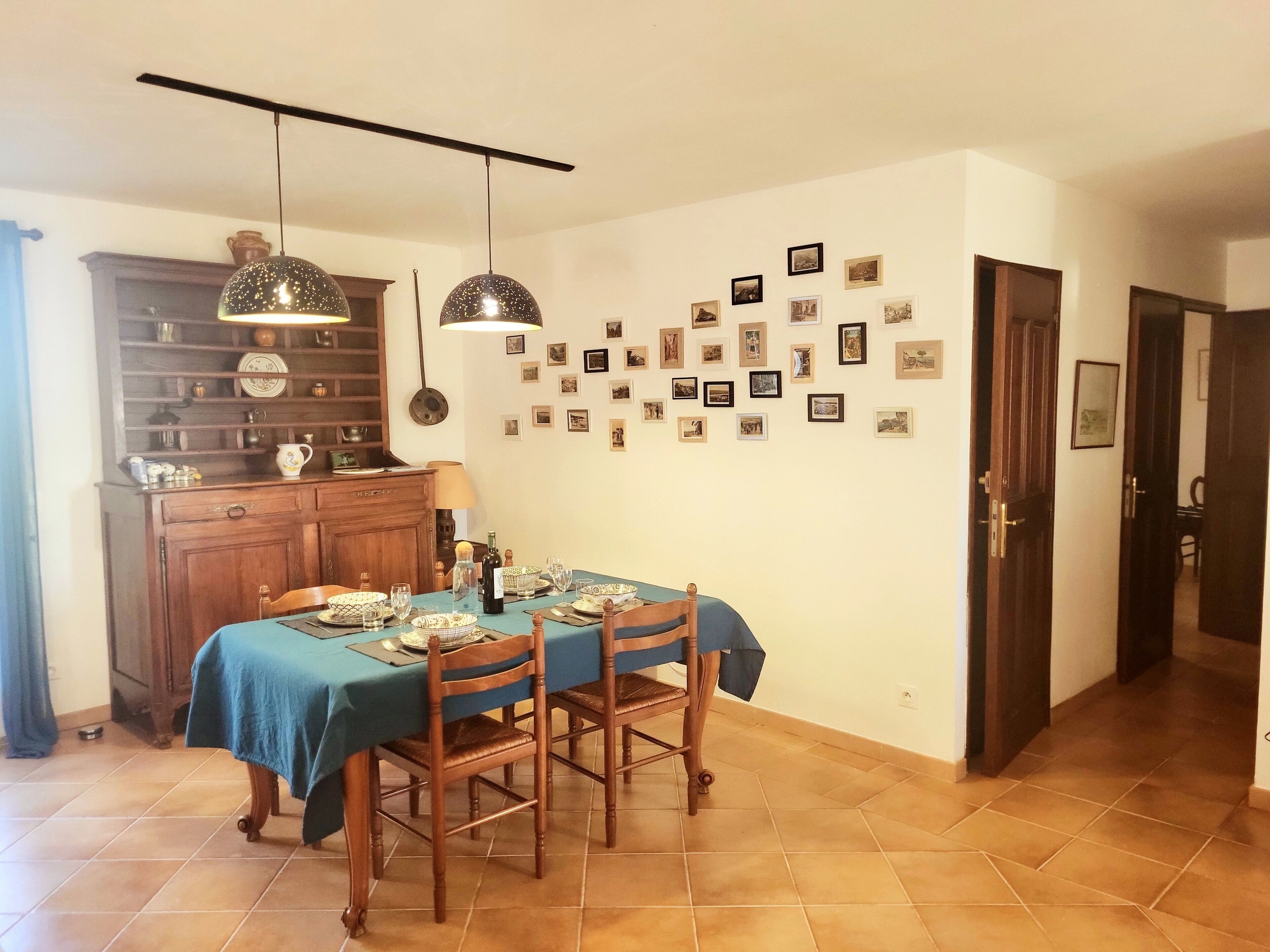 Ein Essbereich mit einem Tisch für vier Personen, einem Holzschrank mit Geschirr und einer Wand mit gerahmten Bildern.