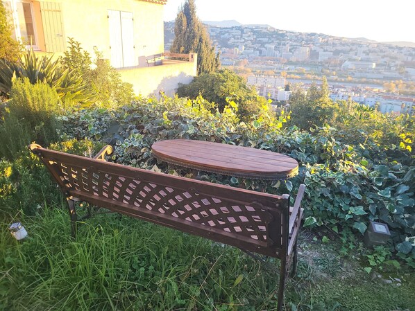 Un conjunto de banco y mesa de madera en un jardín con vistas a la ciudad.