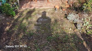 A patio with a table and chairs, a covered area with a door, and a garden with various plants. - Villa 90 m² panoramic view Nice, sea and mountains (Saint-Laurent-du-Var)