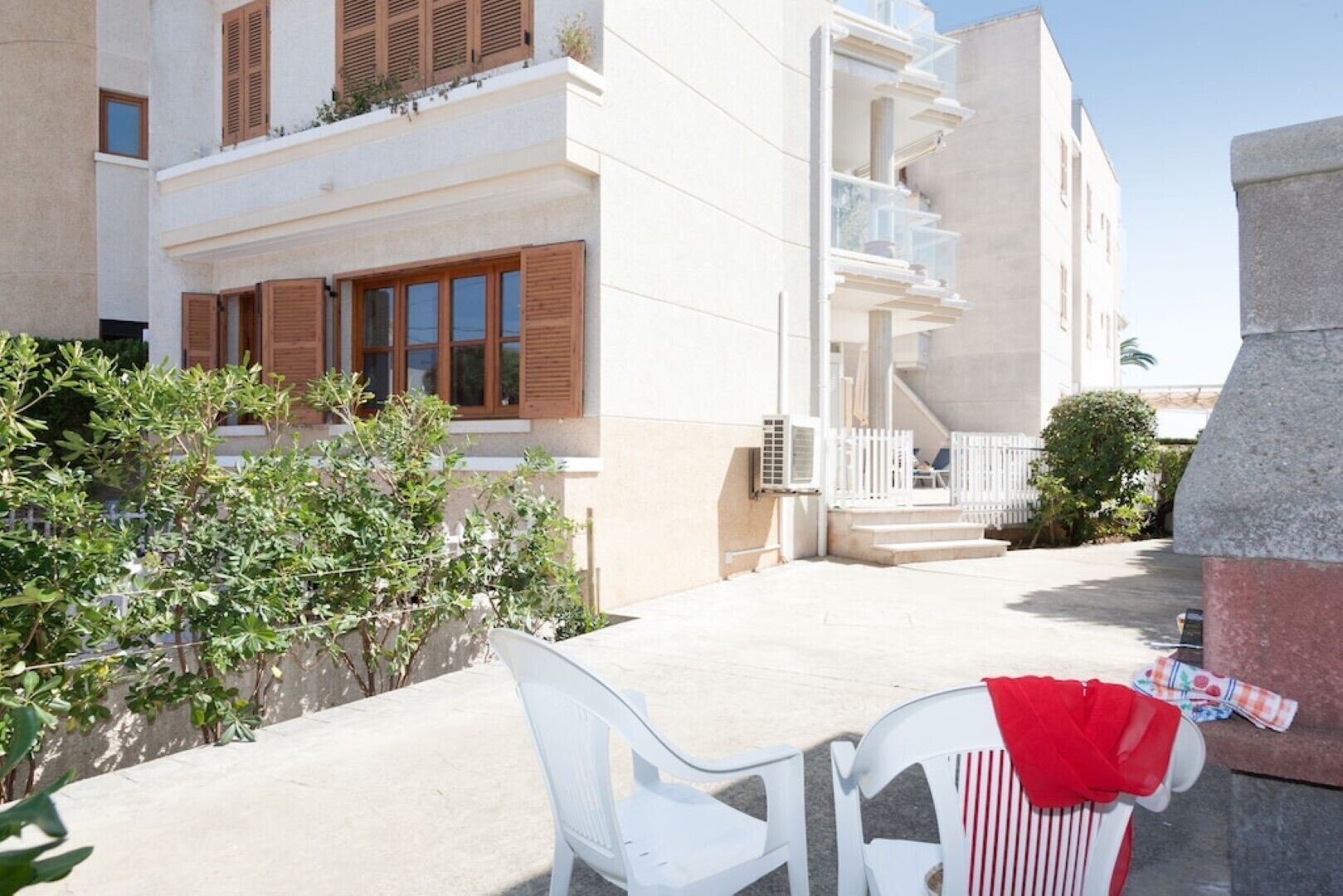 A modern building with a balcony, white walls, and wooden shutters.