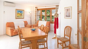 A cozy room with a wooden dining table, orange sofas, and wooden chairs. - 2: GROUND FLOOR- APARTMENT ON THE SEA (Alcúdia)