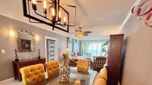 A dining area with a glass-top table, yellow upholstered chairs, a decorative mirror, and a ceiling fan. - The View ll! (Christiansted)