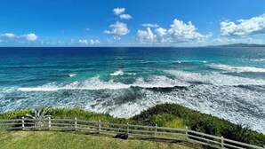 A coastal view with a wooden fence, ocean waves, and a clear sky. - The View ll! (Christiansted)