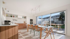 Una cocina moderna con comedor, ventanas amplias y vista al jardín trasero.