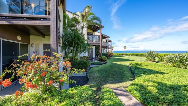 A modern multi-story building with a well-maintained lawn and tropical plants. - Hale Kamaole #170, Fully Renovated, Ground Floor, Full A/C, Near Kamaole III (Kihei)