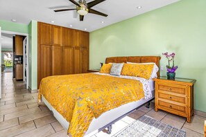 A bedroom with a bed, wooden wardrobe, nightstand, and ceiling fan.