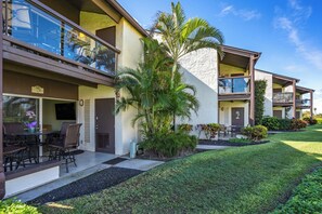 A modern hotel with a two-story structure, outdoor seating area, and a well-maintained lawn.