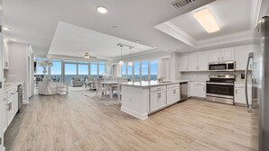 A spacious kitchen with white cabinetry, a large island, stainless steel appliances, and a view to the outside. - New Complex!! New to the Rentals Market.  Beachfront, Lazy River and Slide! (Orange Beach)