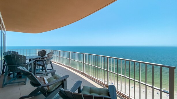 A balcony with a view of the ocean, furnished with chairs and a table. - New Complex!! Beachfront, Lazy River and Slide! Unmatched Views!! (Orange Beach)