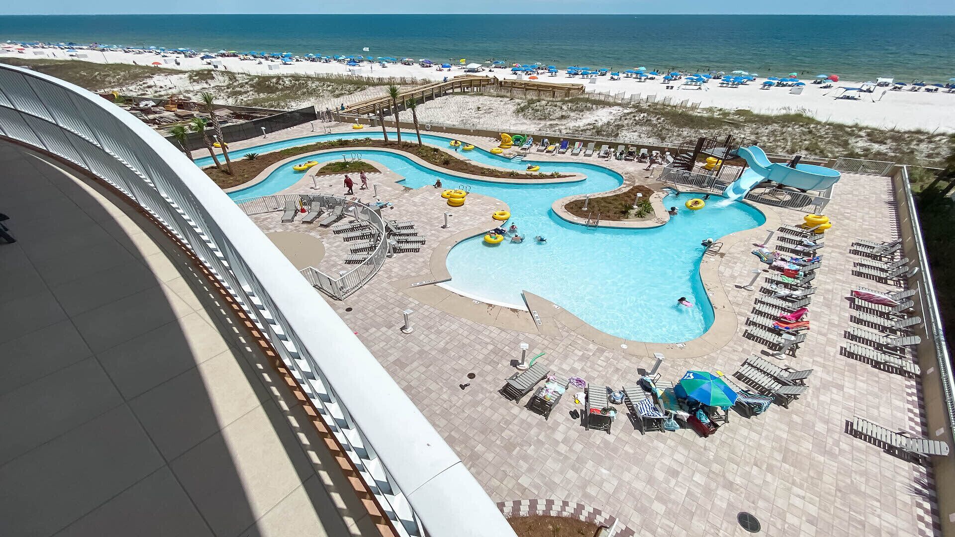 A resort with a pool area, lounge chairs, and a beach.
