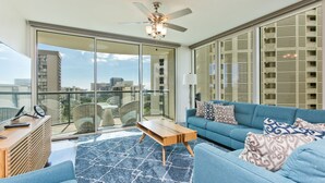 Ein modernes Wohnzimmer mit einem blauen Sofa, einem Holztisch und einem Deckenventilator.